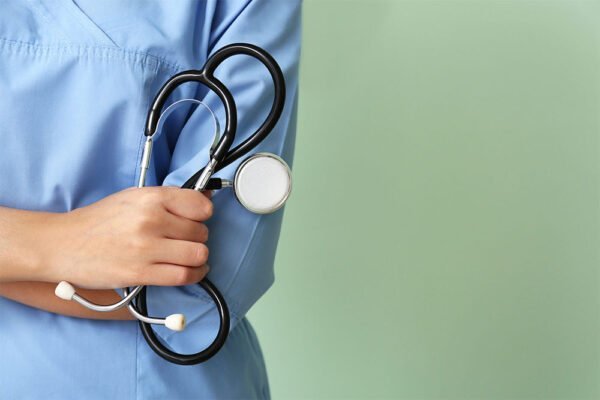 Young nurse with stethoscope on color background, closeup