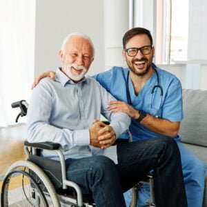 nurse caregiver helping senior man in a wheelchair at home or nursing home