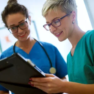 Two nursing remediation students looking at patient records with a smile.