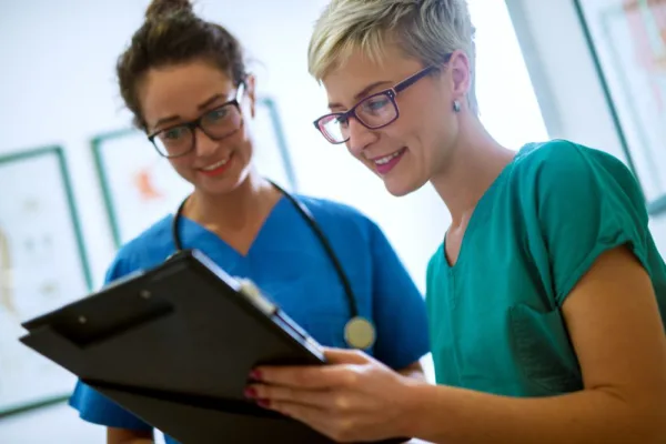 Two nursing remediation students looking at patient records with a smile.