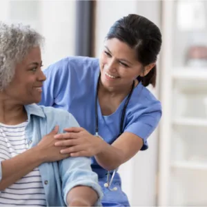 Nurse comforting a patient in a medical setting. Patient is in a wheelchair.